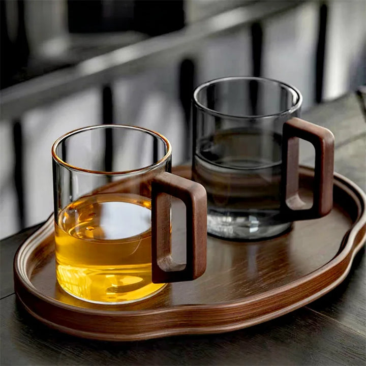 Two glass mugs with wooden handles on a wooden tray.