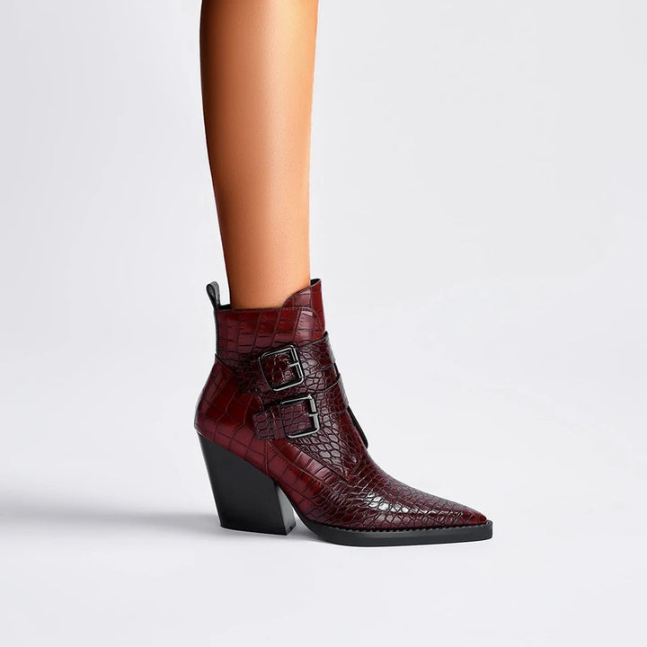 Burgundy crocodile-patterned boot with a black block heel on a light gray background