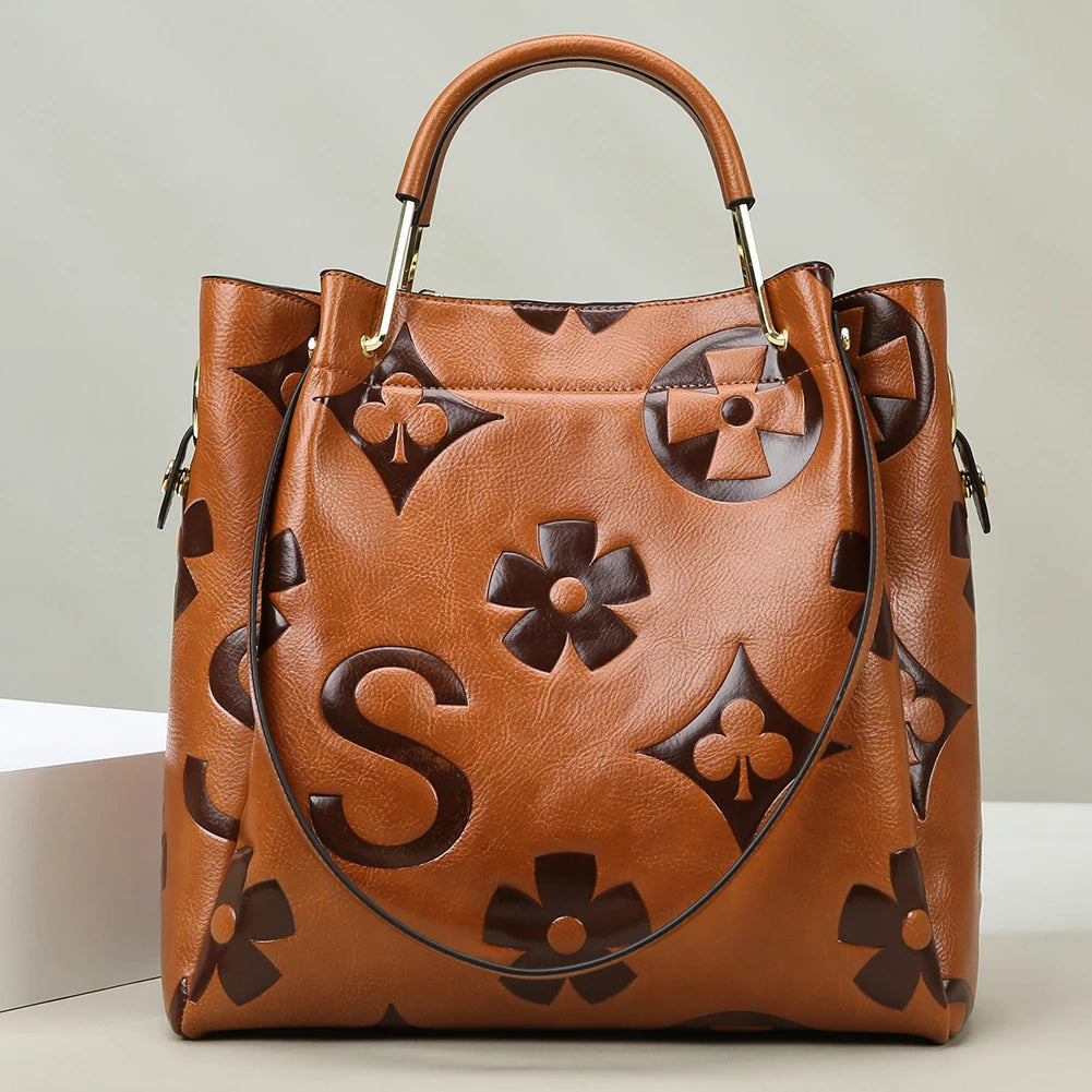 Brown leather handbag with floral patterns on a light background