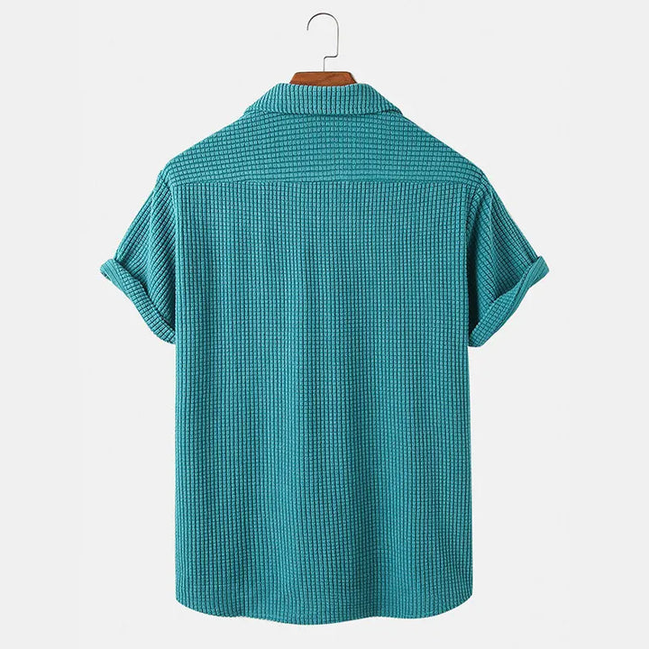 Teal textured shirt on a hanger against a light gray background