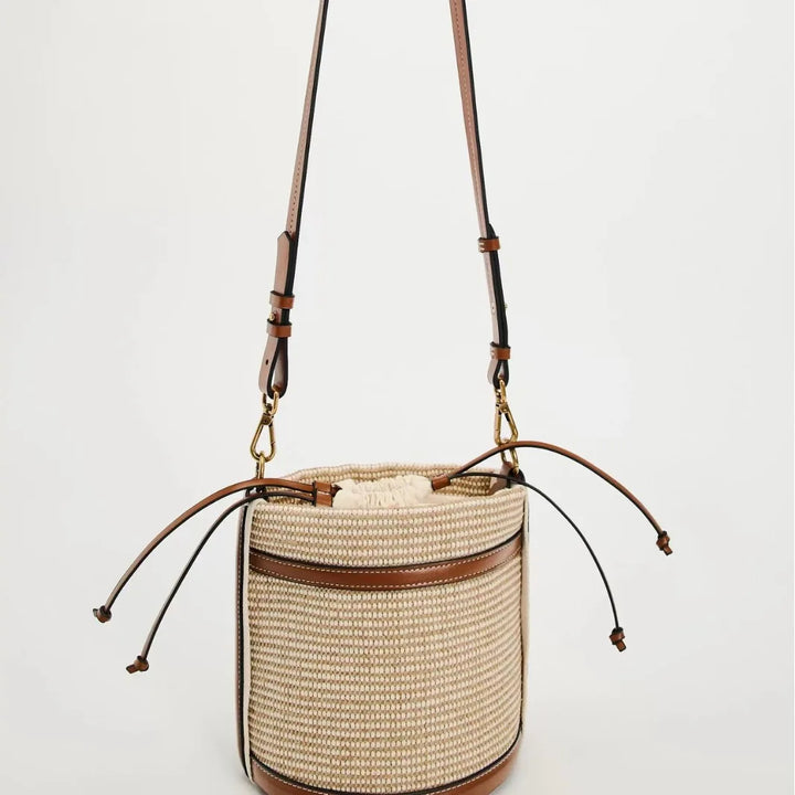 Woven handbag with leather accents on a light gray background