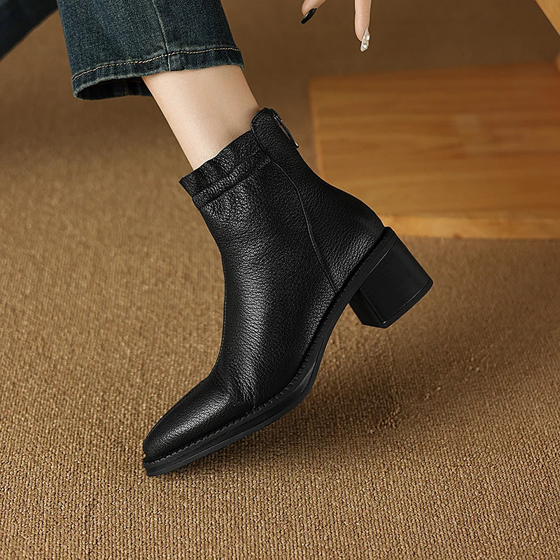 Black ankle boot worn by a person on a brown carpet