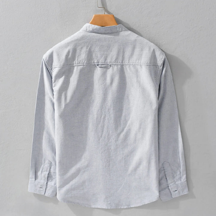 Light gray shirt on a wooden hanger against a gray background