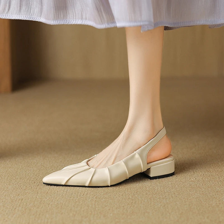 Beige flat shoes worn with a light skirt on a beige background