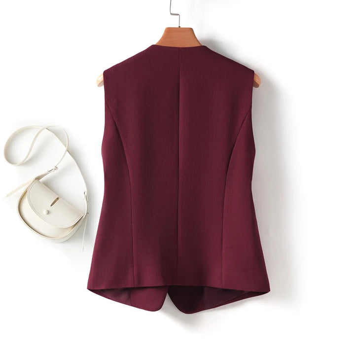 Maroon vest on a hanger with a white handbag on a white background