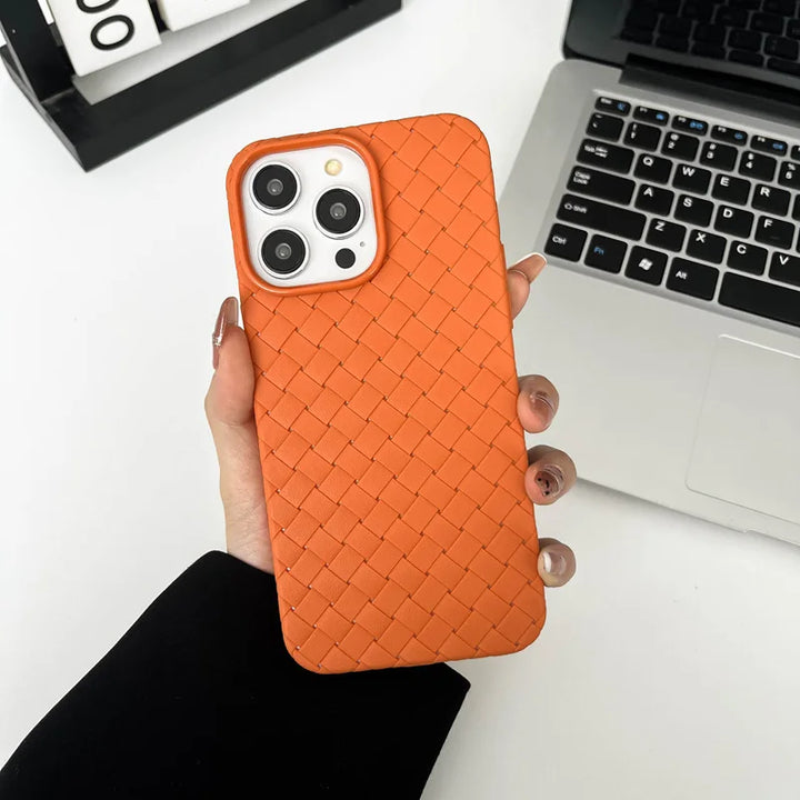 Orange woven phone case held by a hand with a laptop in the background