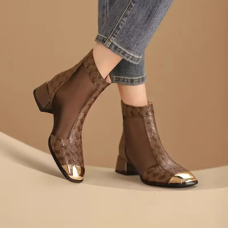 Brown ankle boots with sheer mesh design worn with blue jeans on a beige background