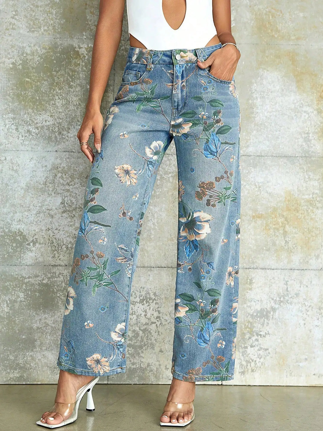 Floral-patterned jeans worn by a person against a textured wall.