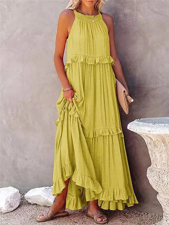 Woman wearing a green tiered dress against a stone wall.