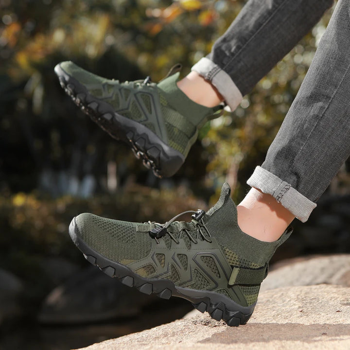 Green hiking shoes worn by a person with a blurred natural background
