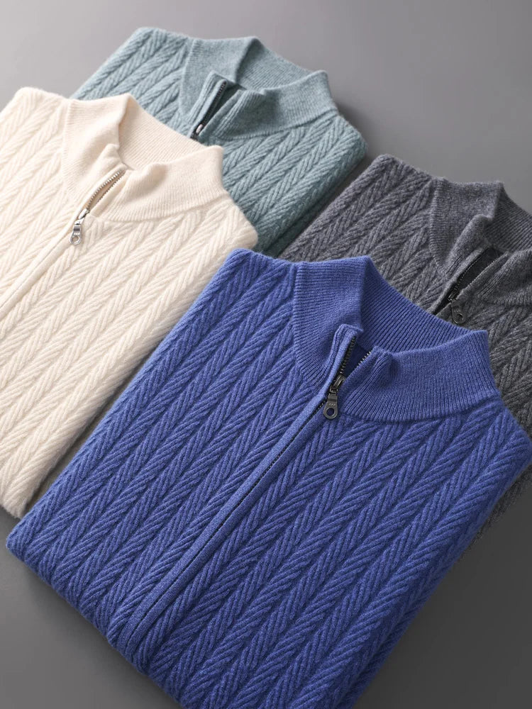 Four folded cable knit sweaters in blue, gray, and white on a gray background