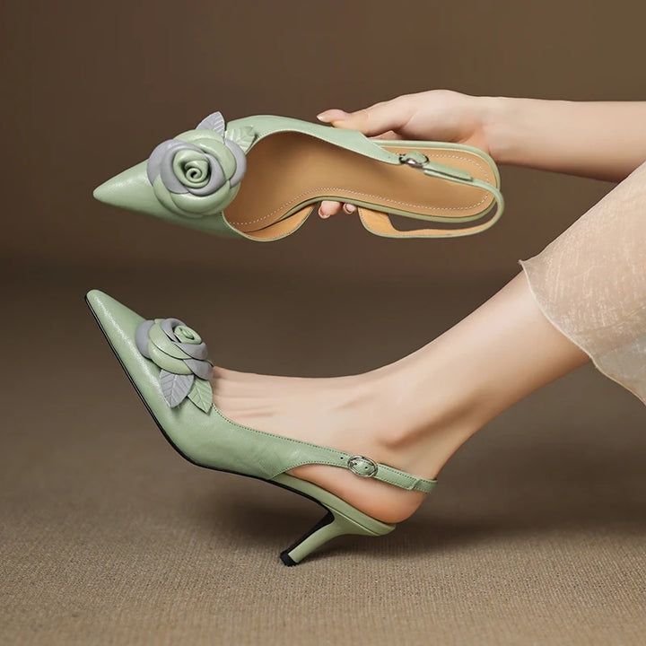 Green high-heeled shoes with floral design worn by a person on a brown background