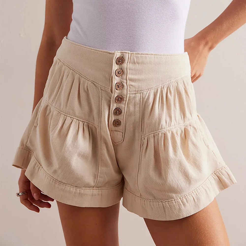 Beige shorts with button details worn by a person on a plain background