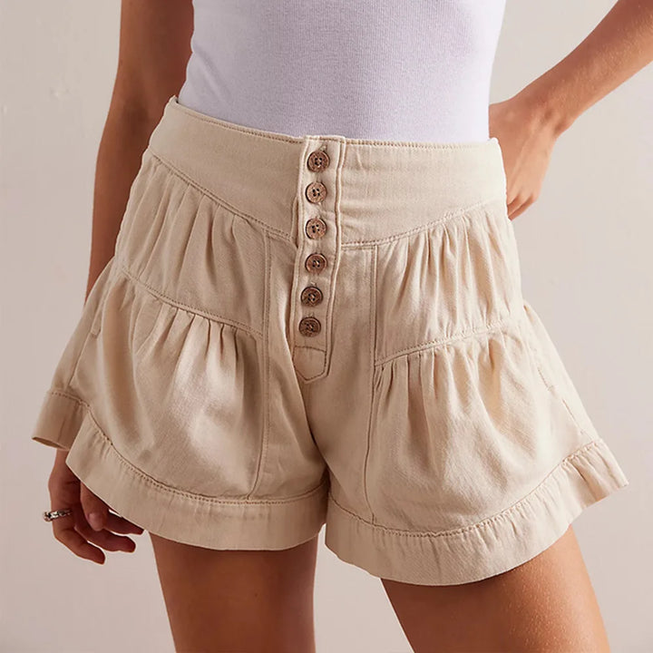 Beige shorts with button details worn by a person on a plain background