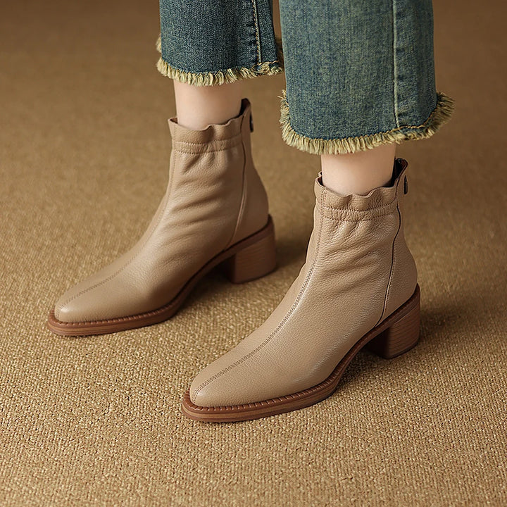 Beige ankle boots worn with blue jeans on a brown background