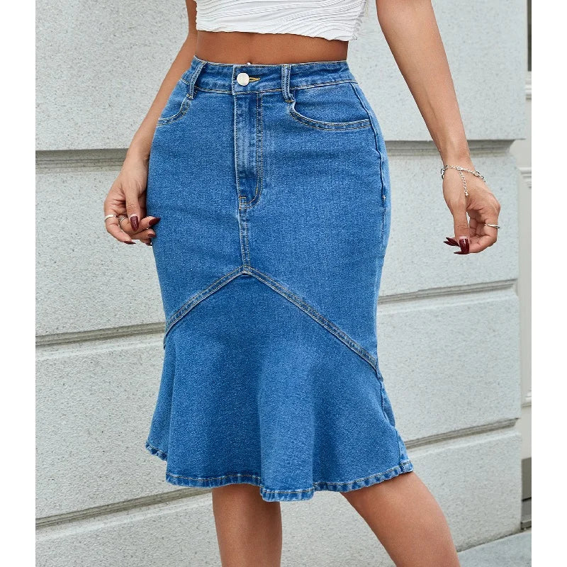 Blue denim skirt worn by a person against a light gray wall.