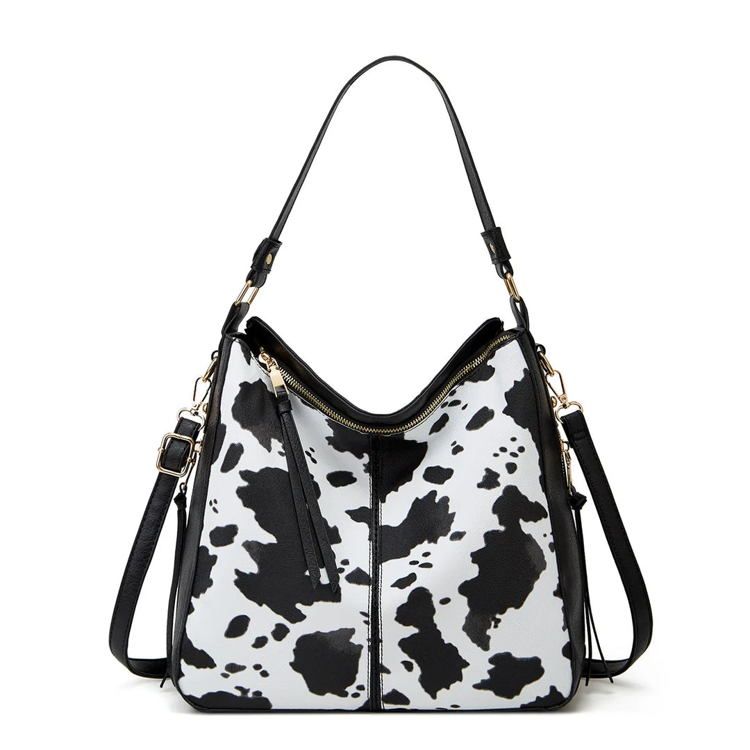 Black and white cow print handbag on a white background