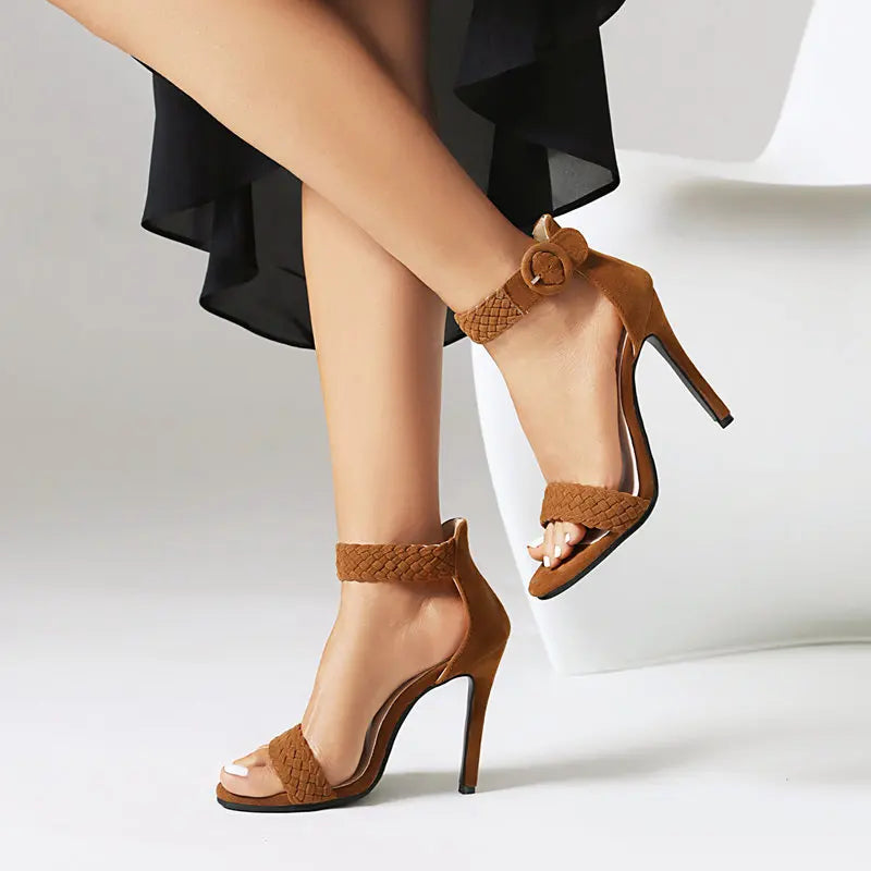 Brown high-heeled sandals with braided straps worn by a person on a light background