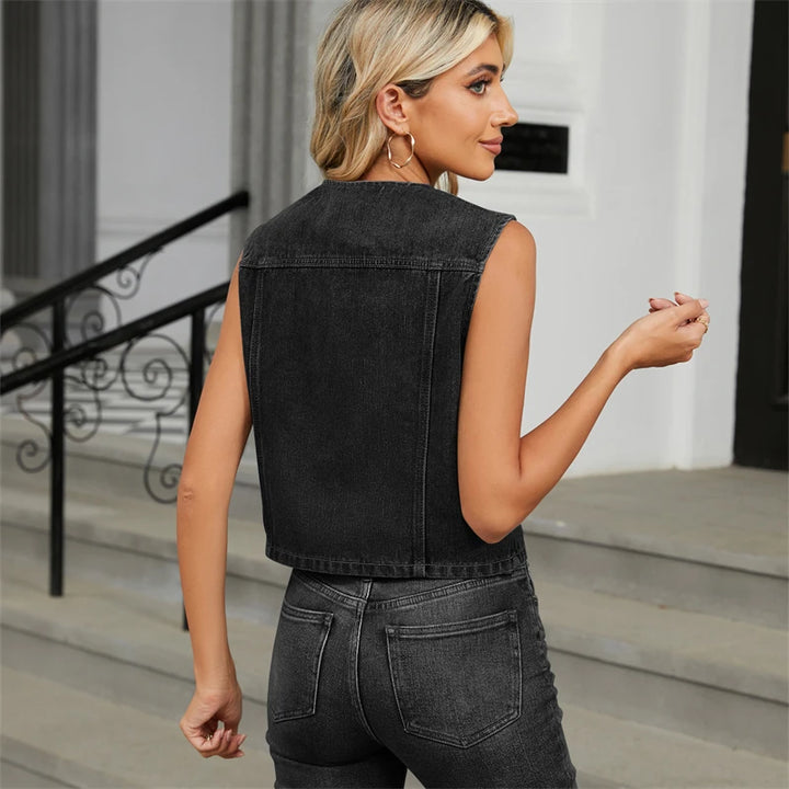 Woman wearing a black denim vest and jeans standing on steps.