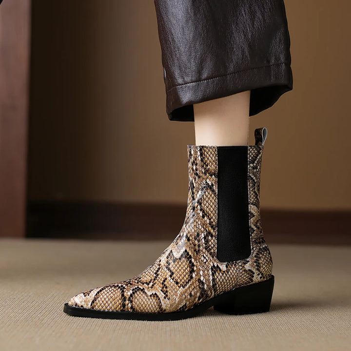 Snakeskin-patterned boot with a black sole on a neutral background