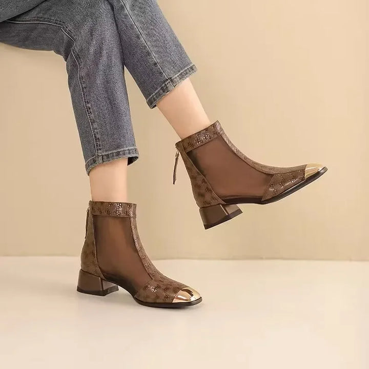 Brown open-toe ankle boots worn with rolled-up jeans on a beige background