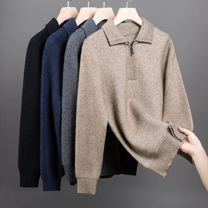 Row of brown, blue, and black sweaters on hangers against a gray background