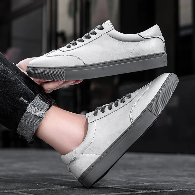 White sneakers with gray soles held by a person against a blurred background