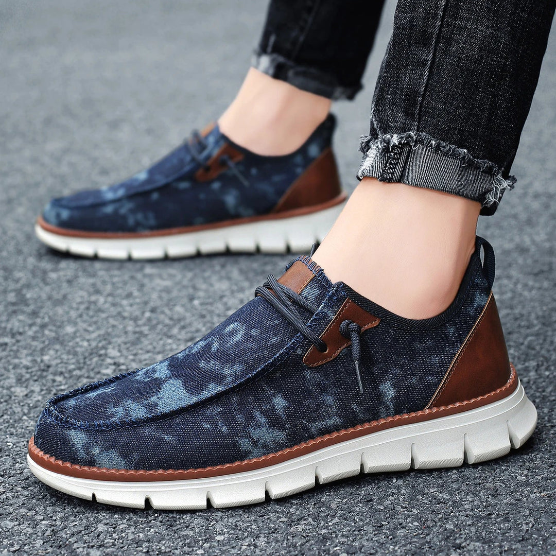 Blue and brown casual shoes worn with black jeans on a road surface