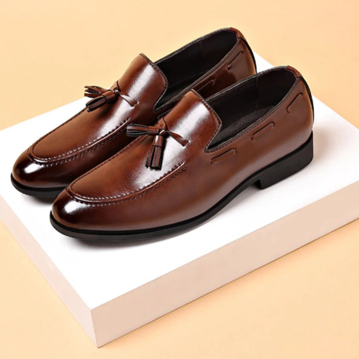 Brown leather loafers with tassels on a beige background