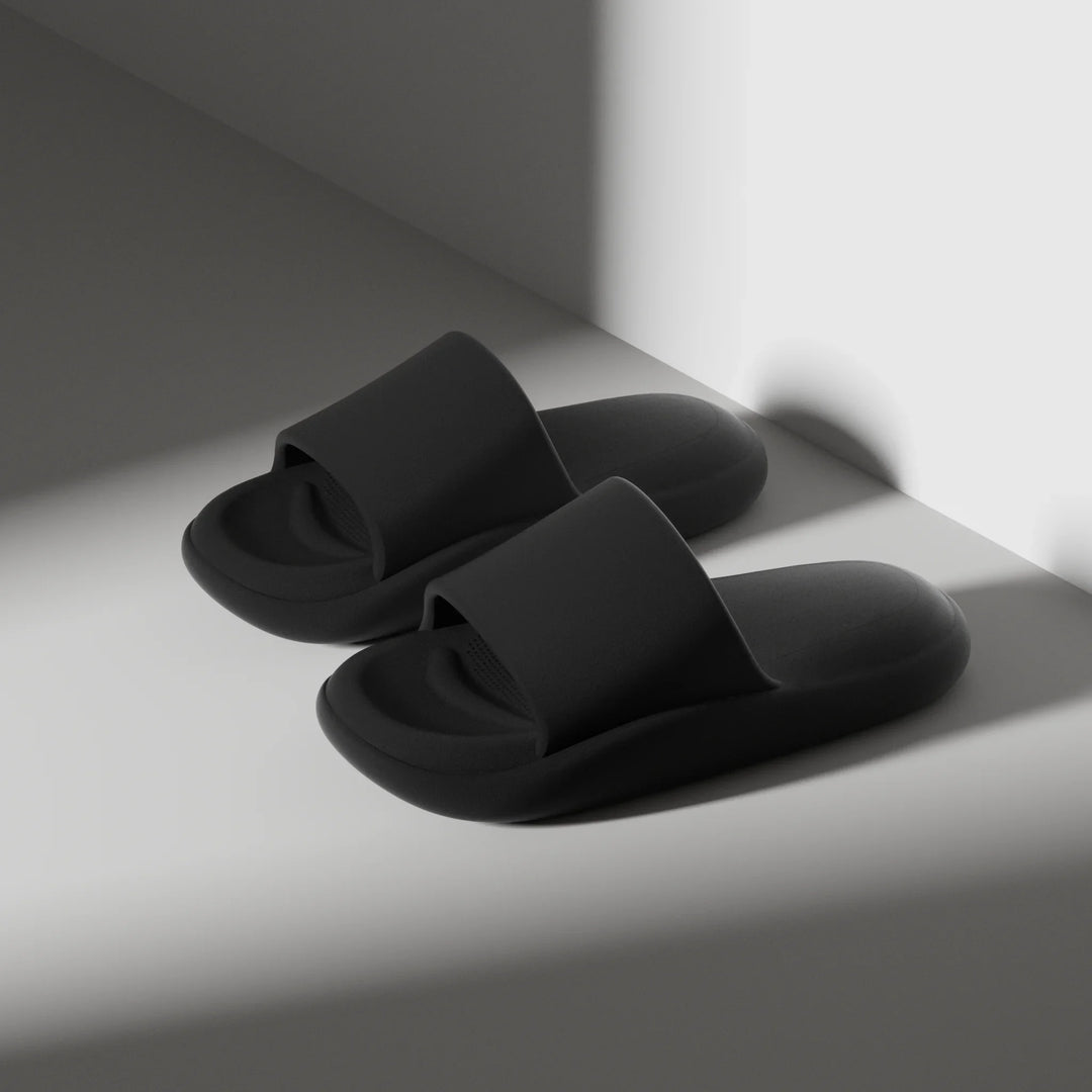 Pair of black slippers on a light surface with a shadow effect