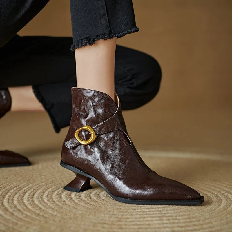 Brown leather boot with gold buckle on a blurred background