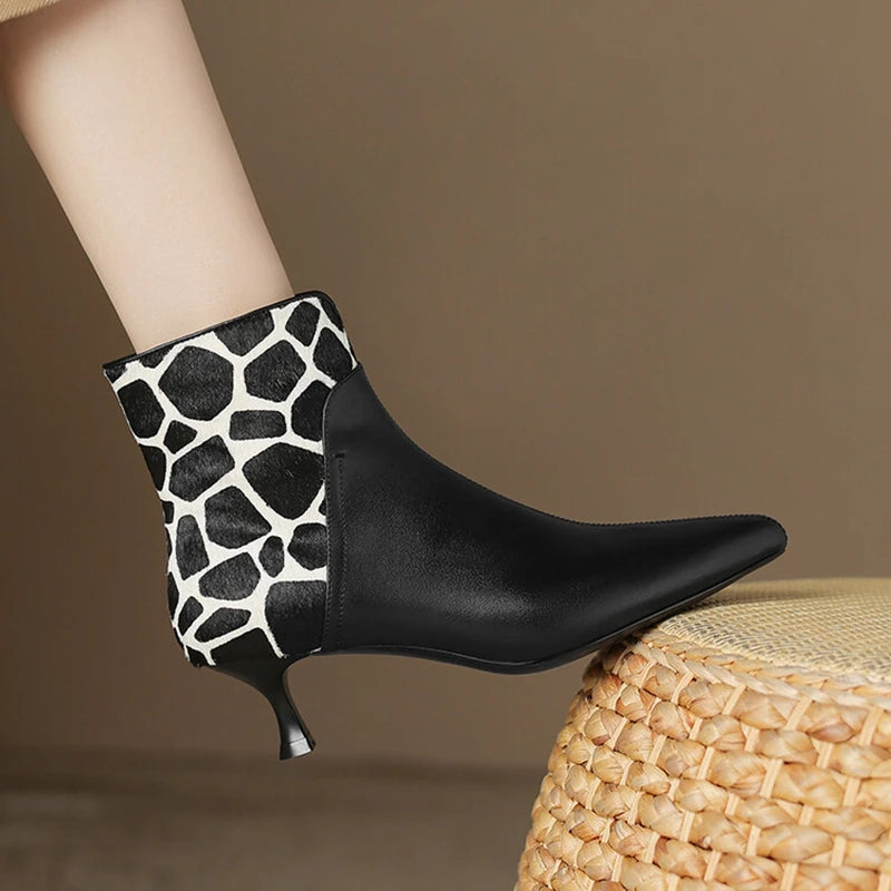 Black ankle boot with white patterned heel on a brown background