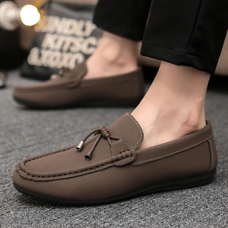 Brown loafers worn by a person on a gray surface