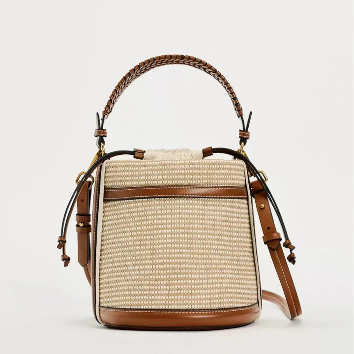 Woven handbag with brown leather accents on a light gray background