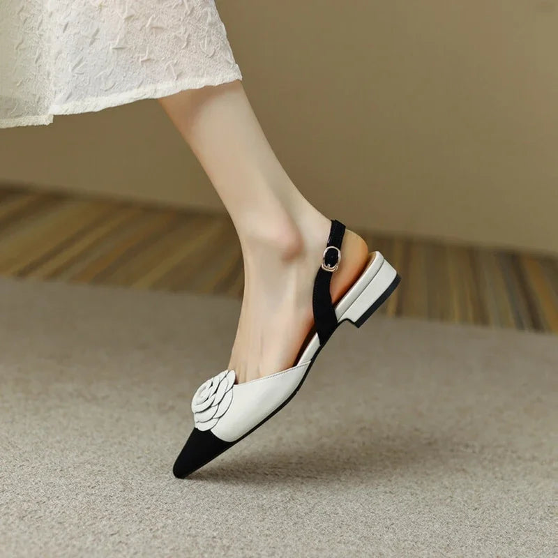 Black and white flat shoes worn by a person on a neutral background