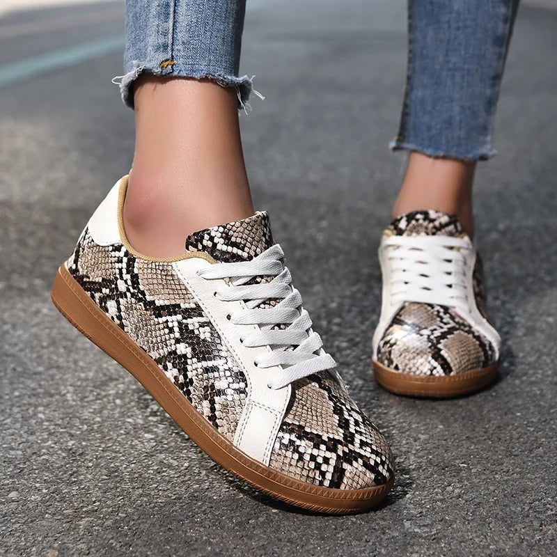 Snakeskin-patterned sneakers with white accents on a pavement background