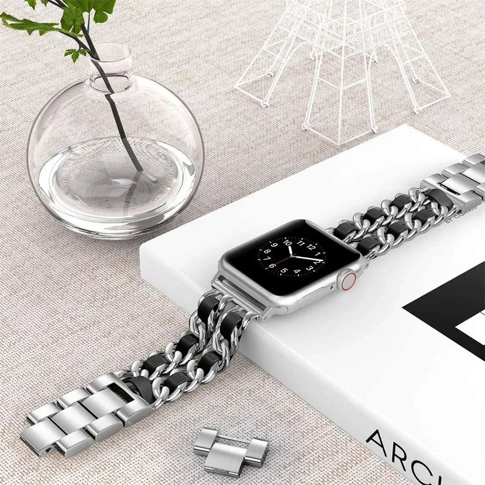 Smartwatch with a chain-style metal band on a light surface with decorative elements.