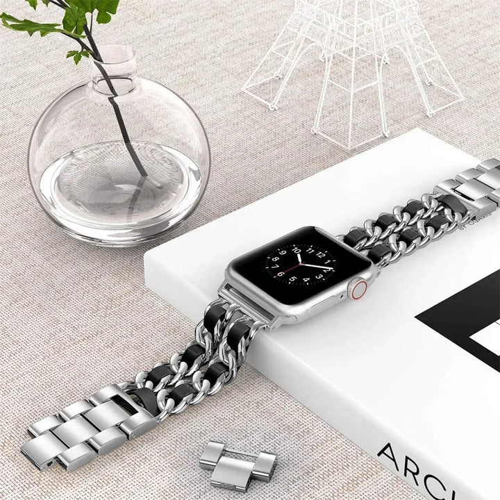 Smartwatch with a chain-style metal band on a light surface with decorative elements.