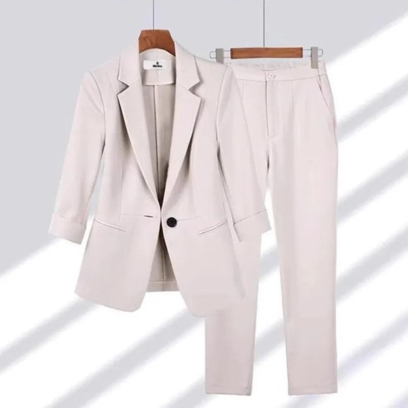 Beige suit jacket and pants on hangers against a light gray background