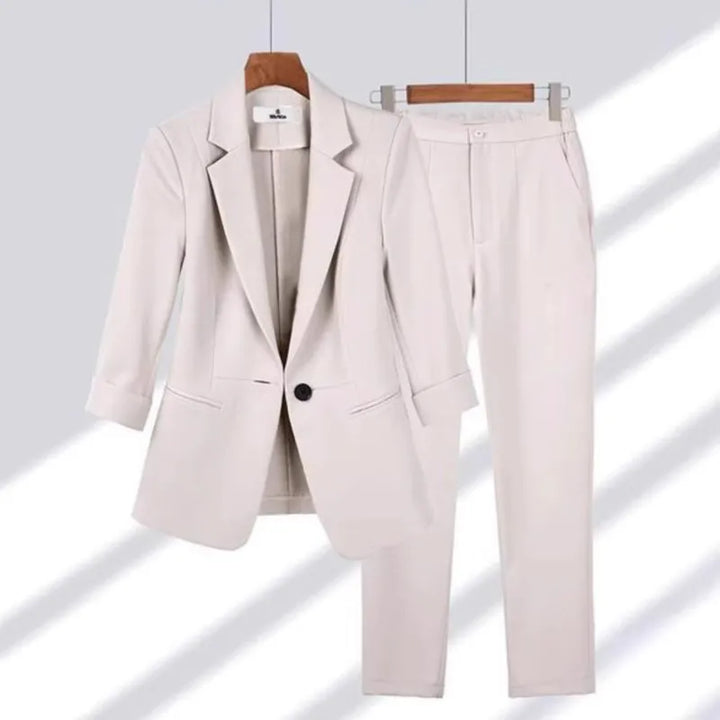 Beige suit jacket and pants on hangers against a light gray background