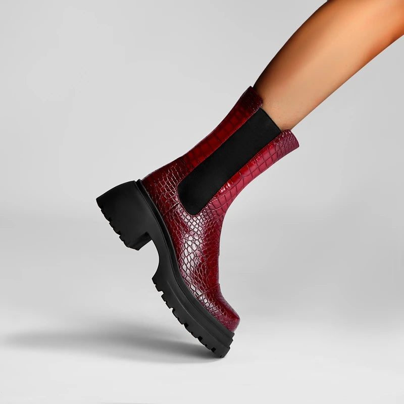 Red crocodile-patterned boot with black sole on a gray background