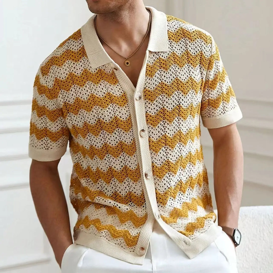 Man wearing a yellow and white patterned cardigan with a blurred background