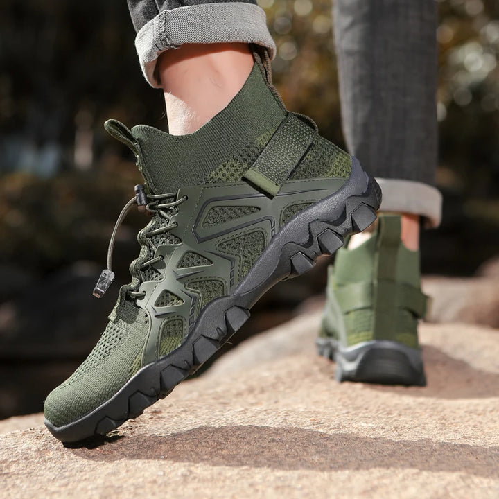 Green hiking boots with black soles worn by a person on a natural path.