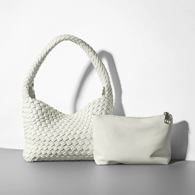 Woven handbag and a white pouch on a light gray surface with a white background