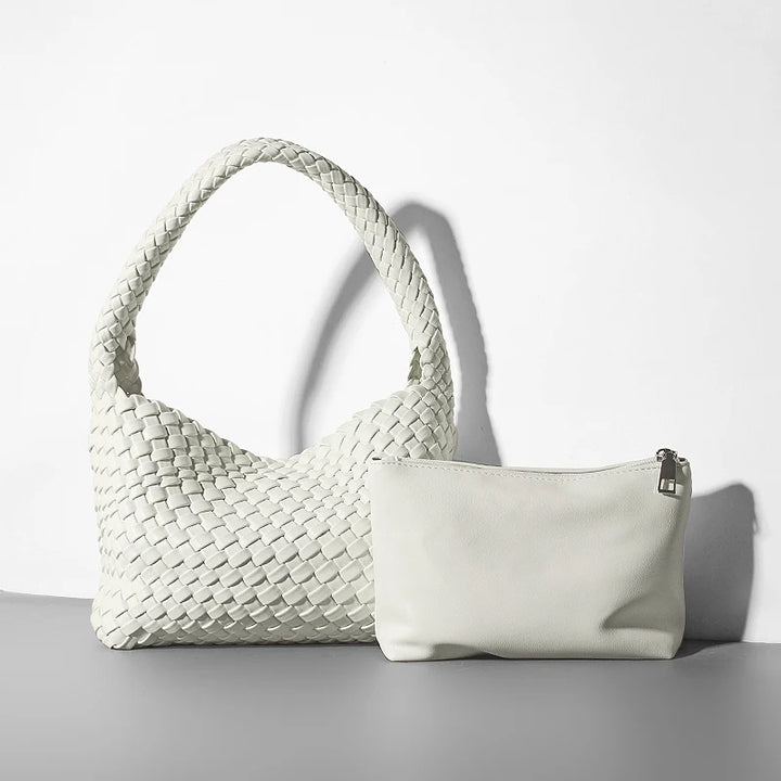 Woven handbag and a white pouch on a light gray surface with a white background