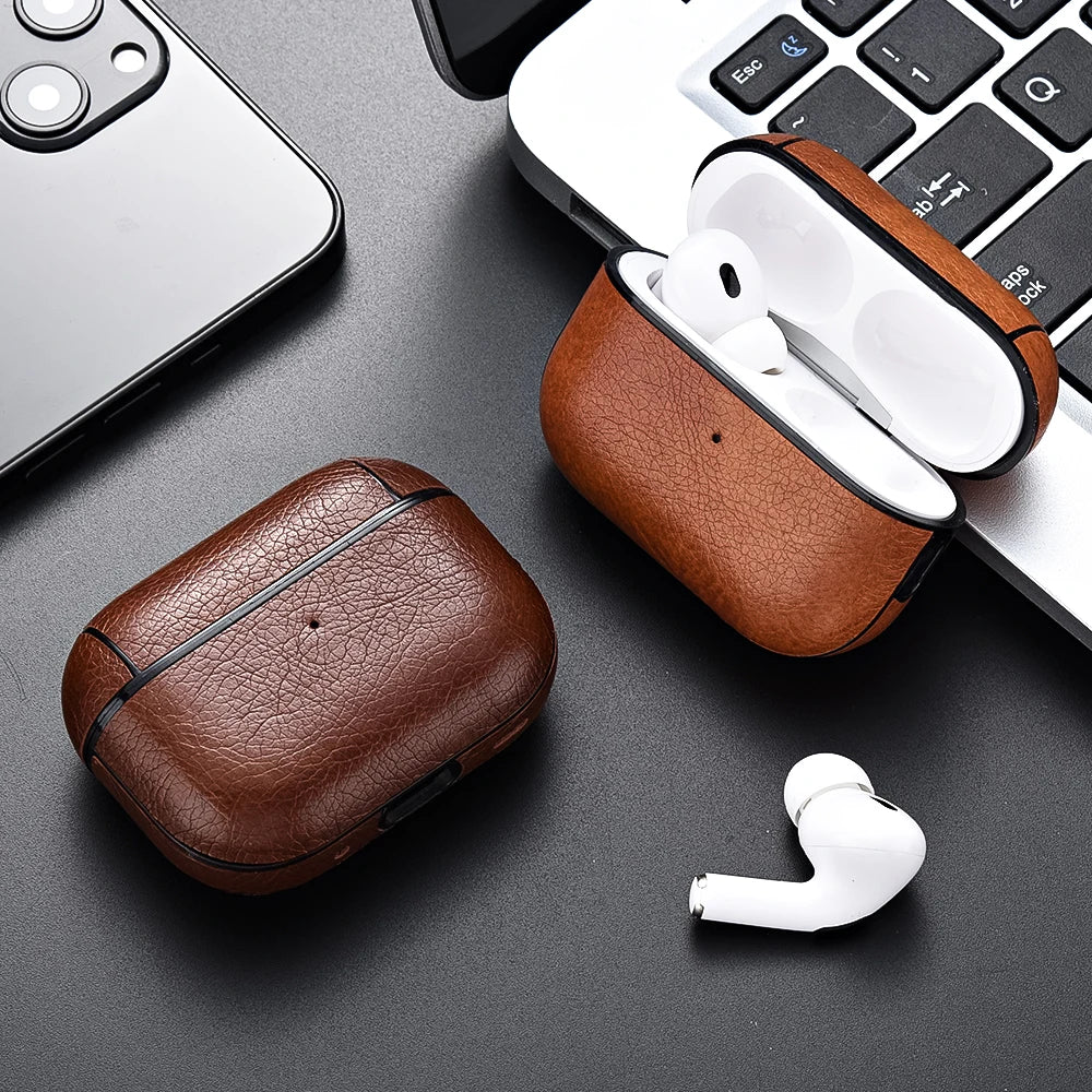 Brown leather cases with white wireless earbuds on a dark surface with a phone and keyboard.