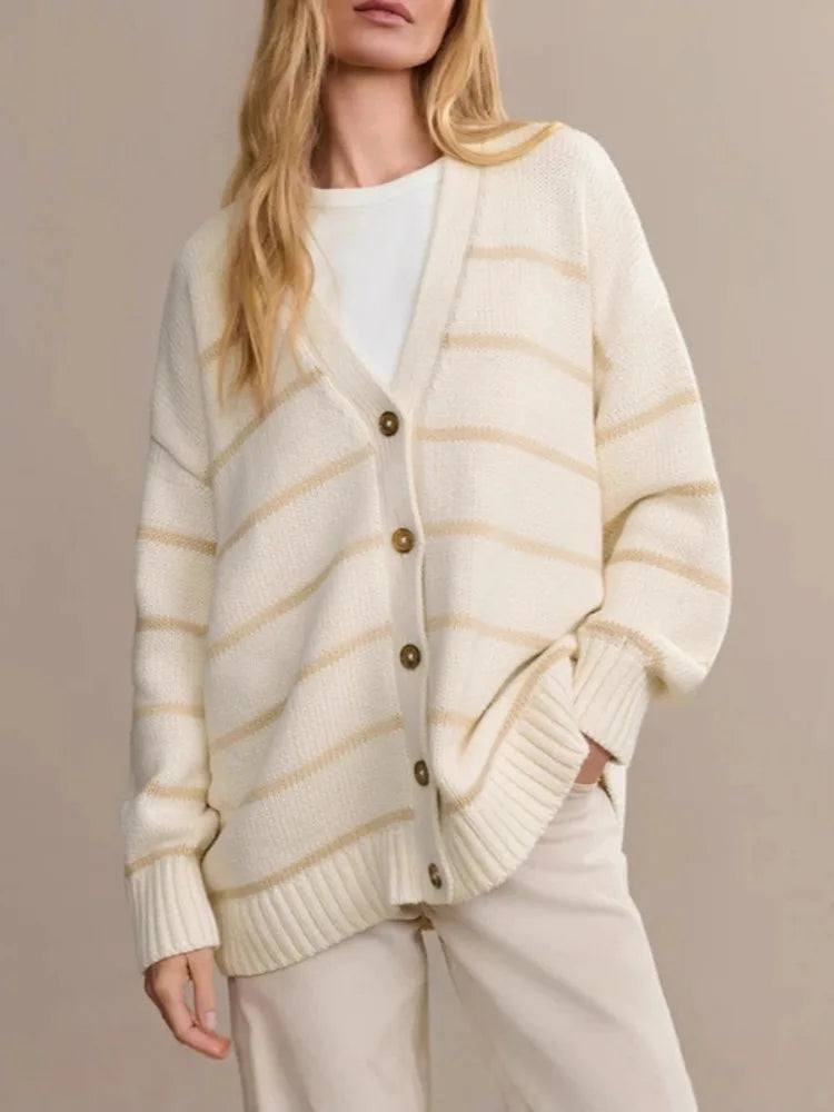 Woman wearing a cream and beige striped cardigan with a plain background