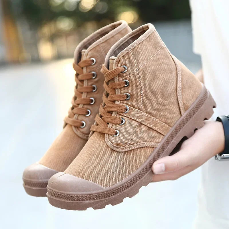 Pair of tan boots held by a person with a blurred background