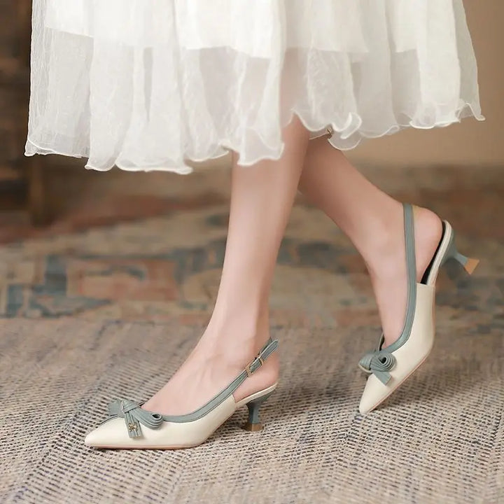White shoes with gray straps worn by a person in a white dress on a textured floor.