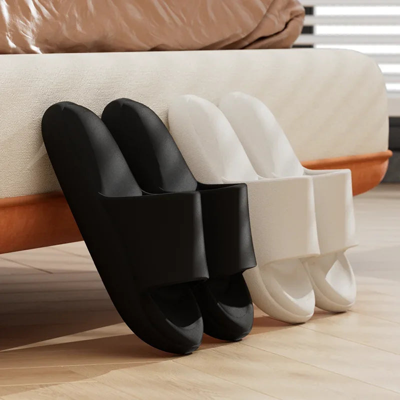 Black and white slippers on a wooden floor with a beige sofa in the background